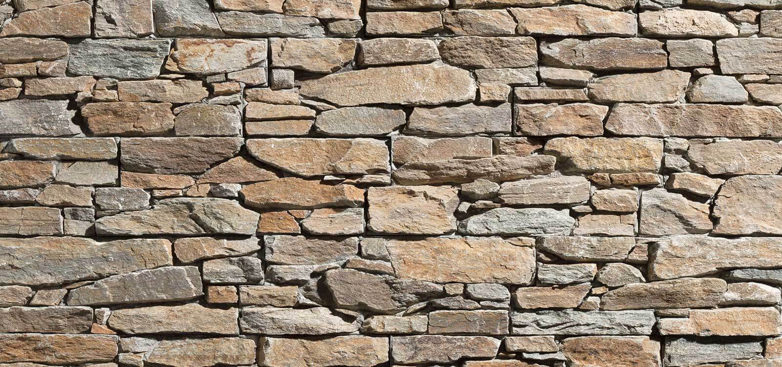 Natural stone wall with an irregular texture in earthy tones, showcasing the raw beauty of stone in its most authentic form.