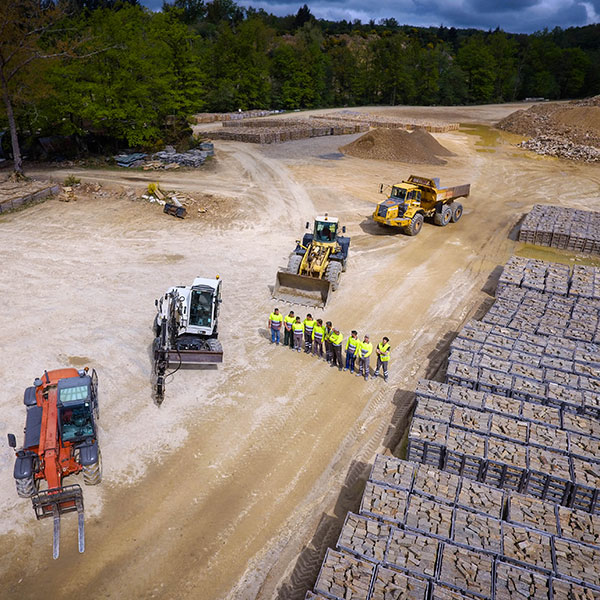 Aerial view of the Saint-Yrieix gneiss quarry, showcasing machinery, workers, and neatly stacked natural stone blocks ready for distribution.