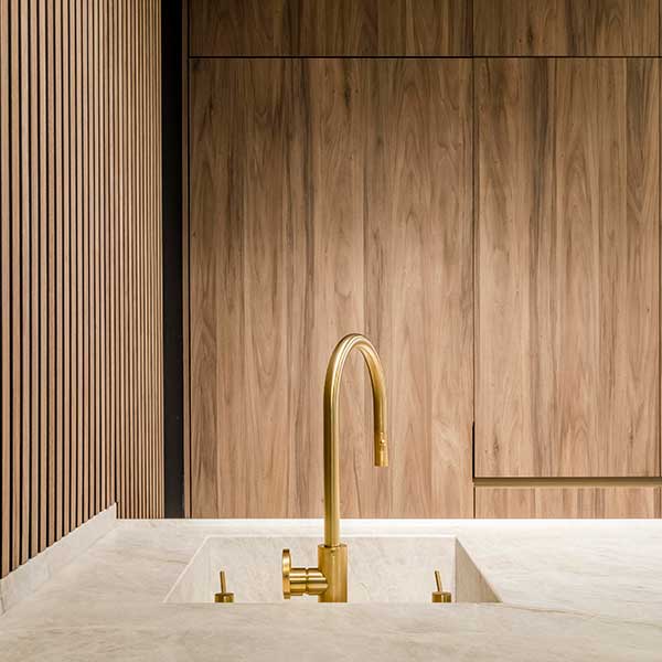 Minimalist kitchen featuring a Parana quartzite countertop by Terra, integrated sink, gold faucet, and warm-toned wooden cabinetry.