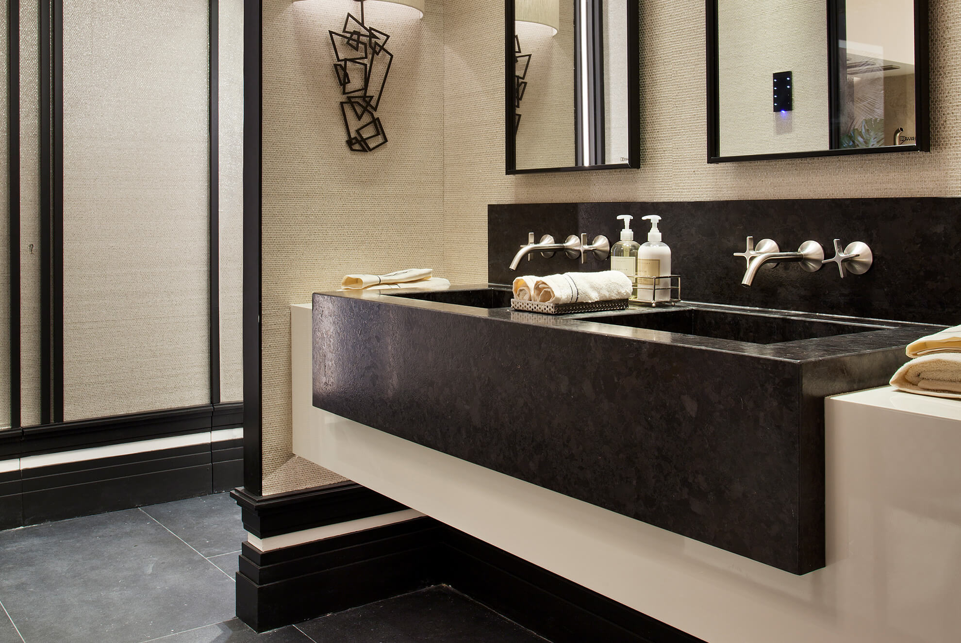 Luxurious bathroom with a floating vanity made of Antique Brown granite, featuring a double integrated sink, wall-mounted faucets, and elegant decor.