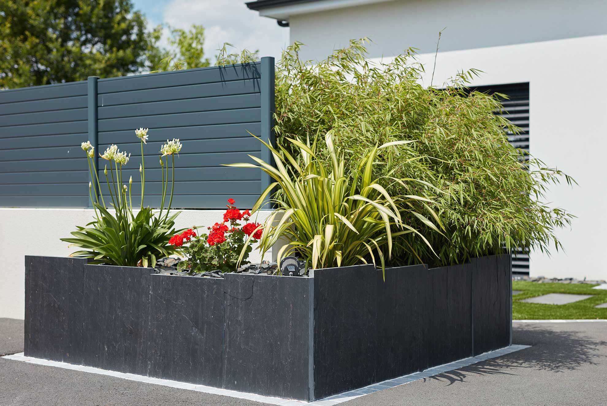 Modern garden design featuring a raised planter with FUJI slate palisades, creating a sleek and natural outdoor setting.