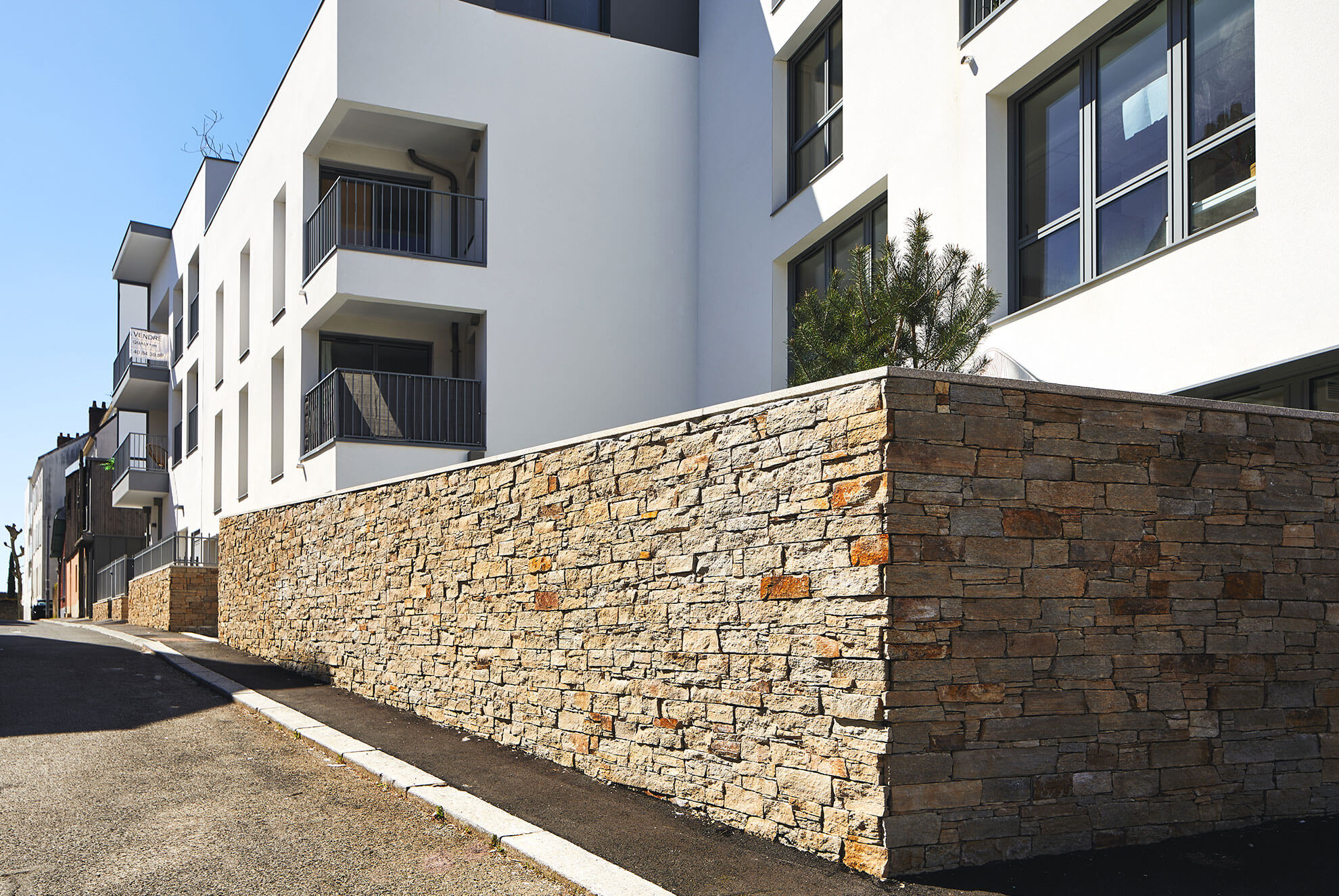 Urban retaining wall featuring STONEPANEL™ Saint Yrieix, adding texture and elegance to the modern architectural setting.