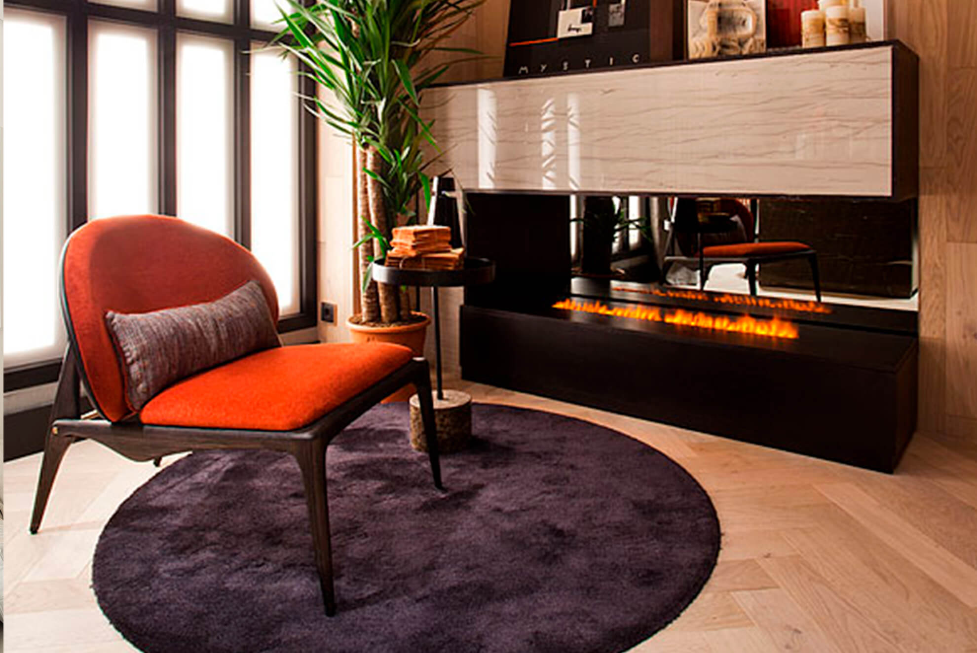 Cozy living space with a modern fireplace clad in Bruma quartzite, a warm-toned accent chair, and a soft circular rug.